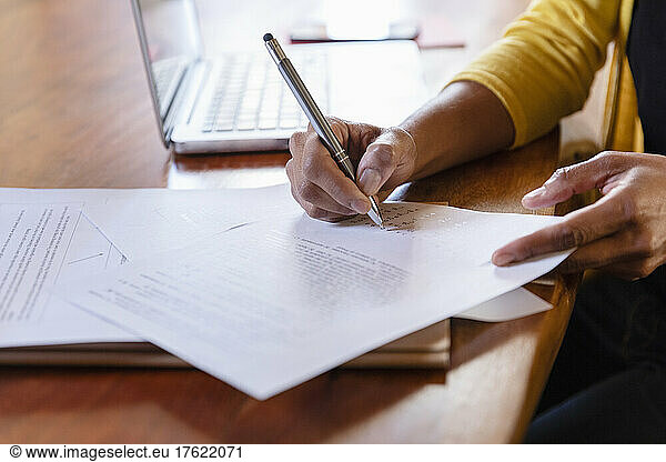 Freelancer signing paper document on desk at home