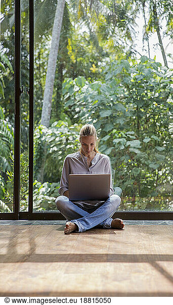 Freelancer sitting on floor and using laptop at home