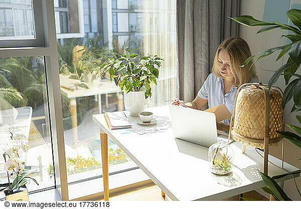 Freelancer sitting with laptop at desk working from home