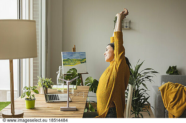 Freelancer stretching arms sitting at desk in home