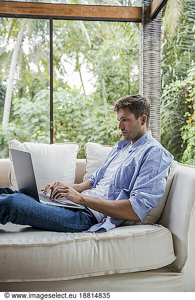 Freelancer using laptop on sofa at home