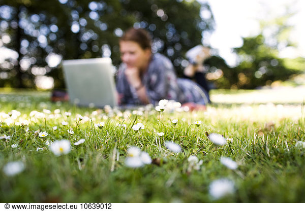 Freelancer using laptop while lying on grass at park