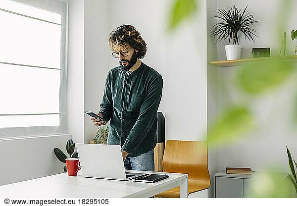 Freelancer using mobile phone at desk in office