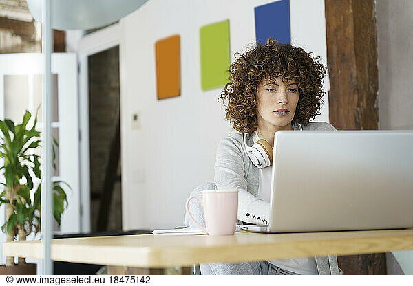 Freelancer with curly hair working on laptop at home