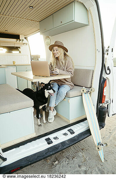 Freelancer with dog working on laptop inside motor home