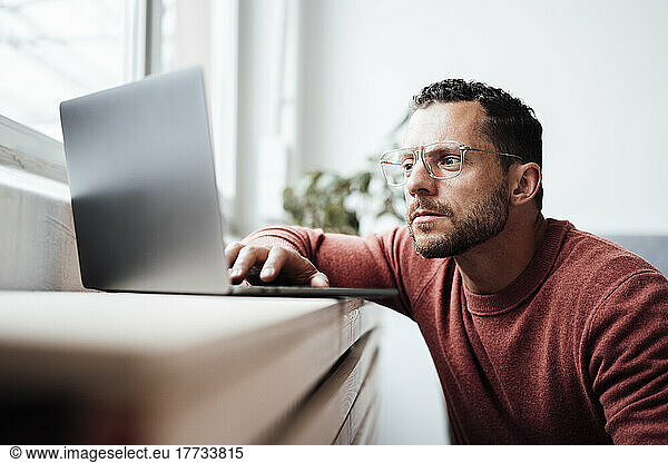 Freelancer with eyeglasses working on laptop at home