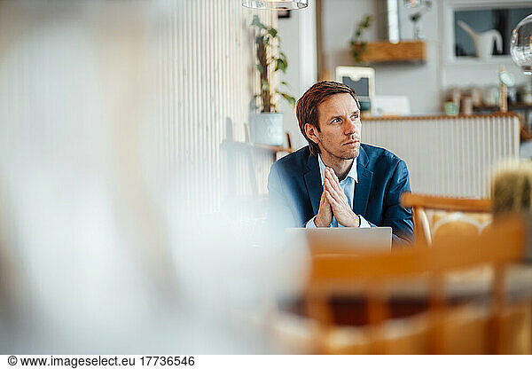 Freelancer with hands clasped sitting in cafe