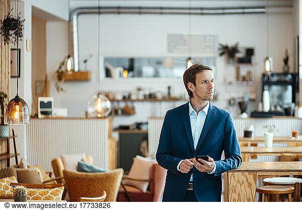 Freelancer with mobile phone standing in cafe