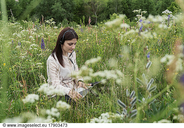 Freelancer working on laptop amidst wildflowers