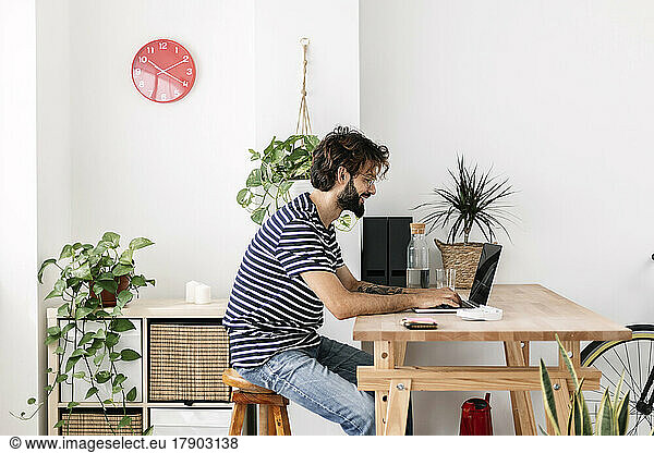 Freelancer working on laptop sitting at desk in home office