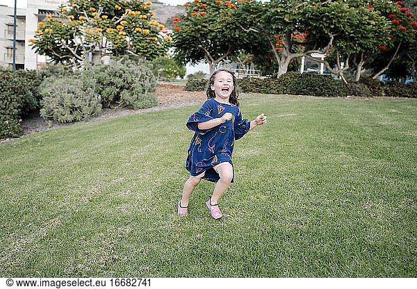 Freigeistiges 3-jähriges Mädchen läuft über den gepflegten Rasen