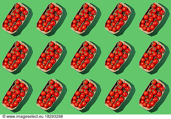 Fresh cherry tomatoes in boxes over green background