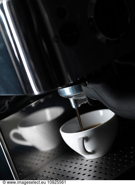 Fresh coffee pouring into white coffee cup from coffee machine