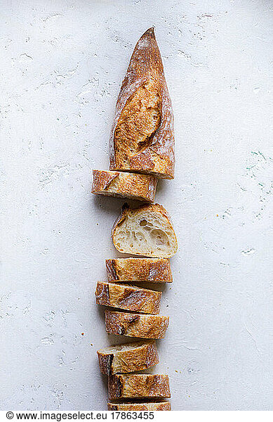 fresh french baguette slices arranged in a loaf on a white background