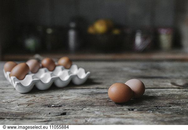 Fresh hen's eggs in a box and on a wooden table.