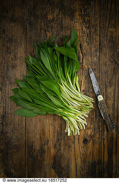 Fresh ramson and kitchen knife lying on wooden surface