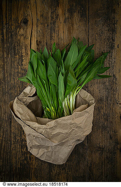 Fresh ramson in paper bag lying on wooden surface
