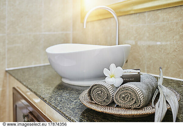 Fresh rolled towels and soap bars with frangipani flower in bathroom