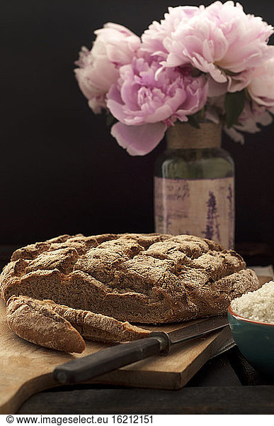 Fresh rye bread with knife on chopping board, close up