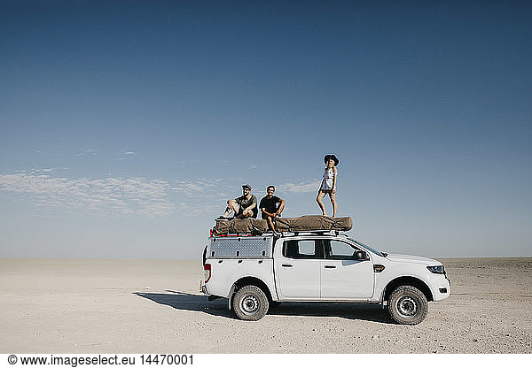 Freunde auf einer Safari  auf ihrem Geländewagen stehend