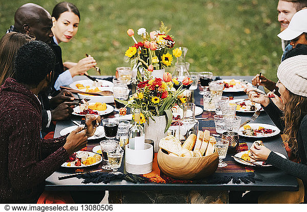 Freunde essen Essen  während sie im Garten am Esstisch sitzen