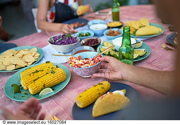 Freunde essen Tacos und Mais am Terrassentisch