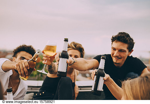 Freunde feiern mit Bier  während sie auf dem Dach der Stadt feiern