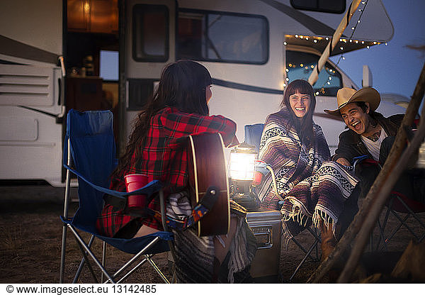 Freunde genießen beim Camping gegen Wohnmobil in der Nacht