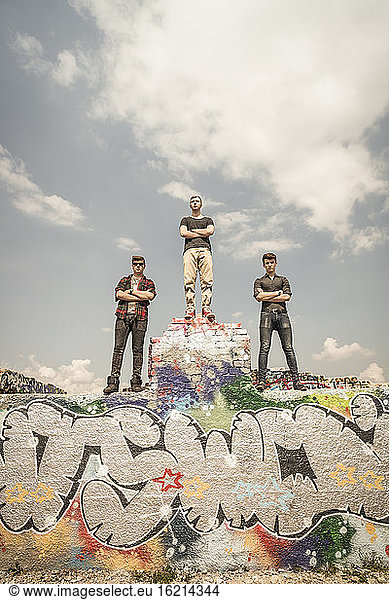 Freunde im Teenageralter stehen an einer Graffiti-Wand in einem alten  heruntergekommenen Industriegebiet