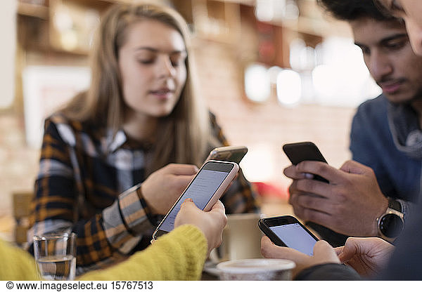 Freunde junger Erwachsener benutzen Smartphones im Café