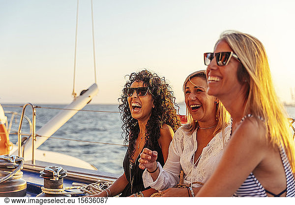 Freunde lachen während der Bootsfahrt im Abendlicht