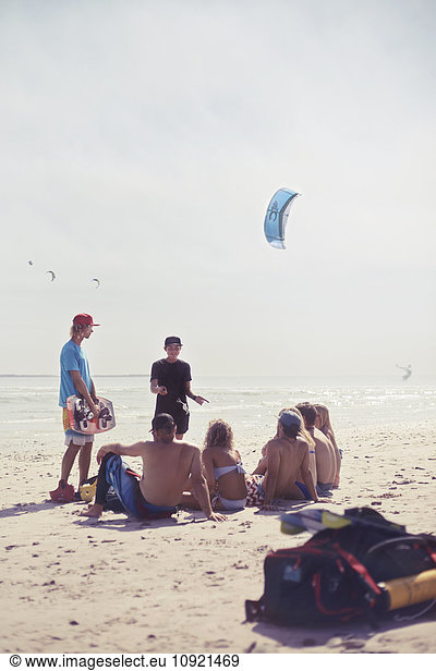 Freunde lernen Kitesurfen am sonnigen Strand