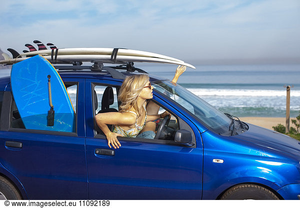 Freunde mit Surfbrettern im Auto an der Küste