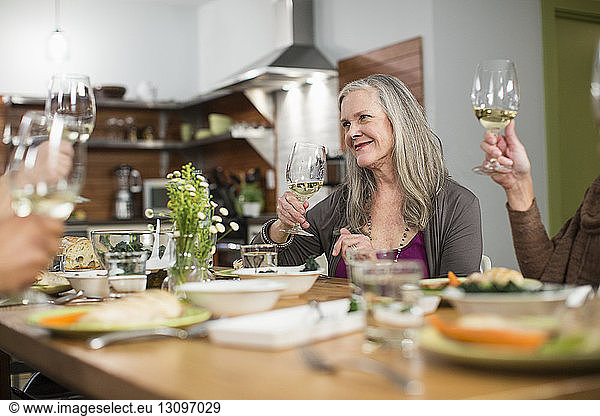 Freunde mit Weingläsern sitzen bei geselligem Beisammensein am Tisch