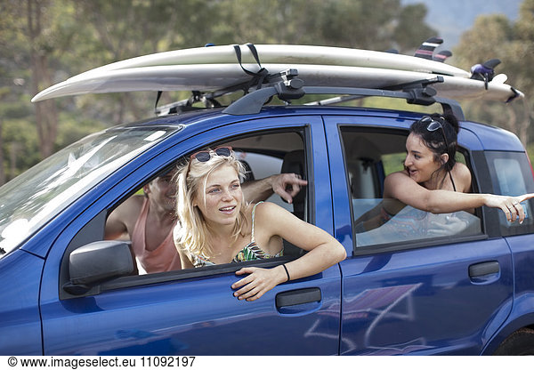 Freunde omn eine Fahrt im Auto mit Surfbrettern auf dem Dach