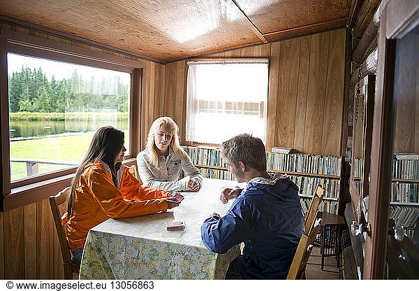 Freunde spielen Karten am Tisch im Blockhaus