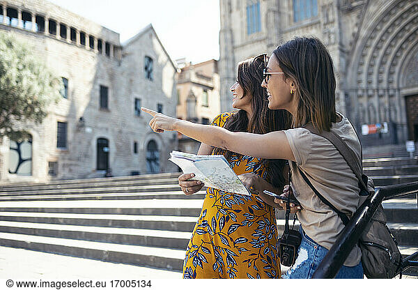 Freunde studieren eine Landkarte  während sie auf dem Platz der Kathedrale von Barcelona in Barcelona  Katalonien  Spanien stehen
