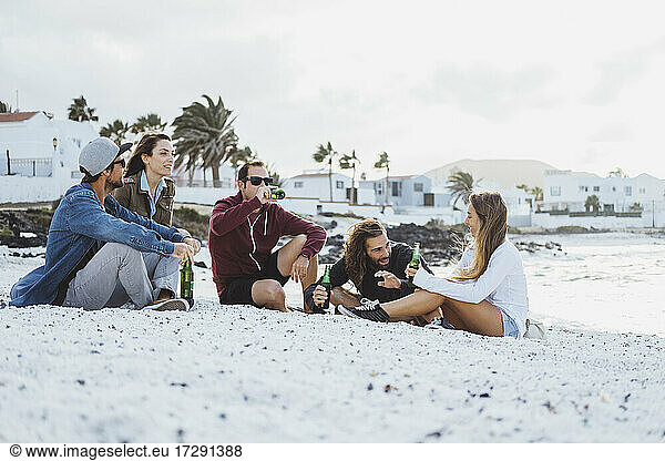 Freunde unterhalten sich bei einem Drink am Strand