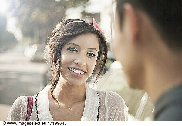Freundin lächelt beim Anblick ihres Freundes an einem sonnigen Tag