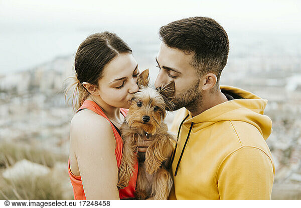 Freundin und Freund küssen Haustier zusammen