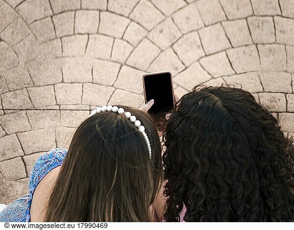Freundin zeigt ihren Handy-Bildschirm  zwei Mädchen zeigen auf ihr Handy  Mädchen zeigt ihr Smartphone ihrer Freundin
