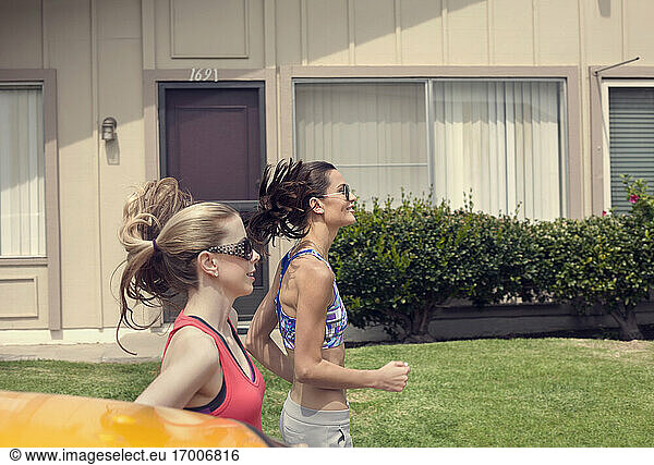 Freundinnen joggen in einem Vorort an einem sonnigen Tag