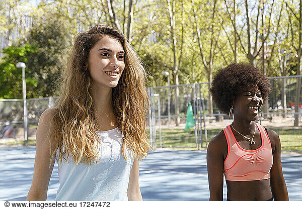 Freundinnen lächelnd und wegschauend auf dem Sportplatz