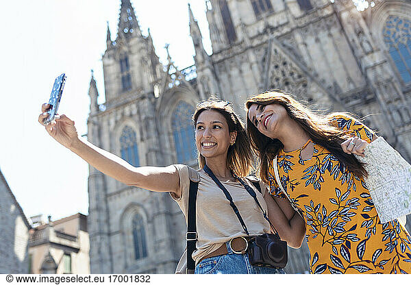 Freundinnen machen ein Selfie mit ihrem Mobiltelefon auf dem Platz der Kathedrale von Barcelona in Barcelona  Katalonien  Spanien
