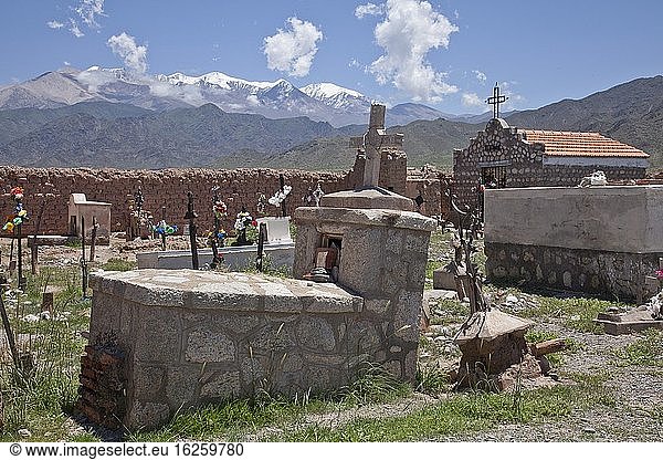 Friedhof mit Kreuzen mit dem schneebedeckten Gebirge Nevado Cachi in der Andenregion,  Salta,  Argentinien.