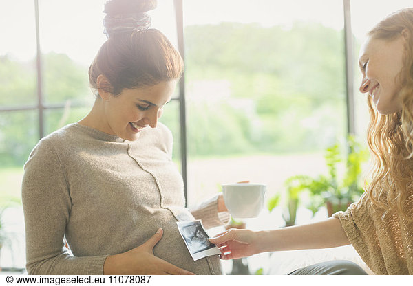 Friend holding ultrasound to pregnant womanís stomach