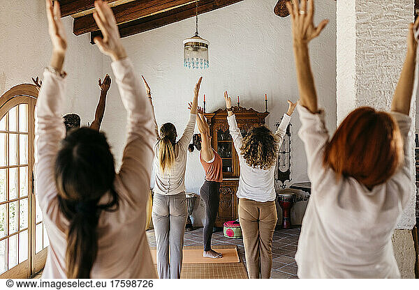 Friends and yoga instructor stretching hands in yoga studio