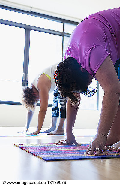 Friends bending while exercising in yoga studio