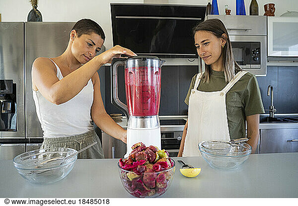 Friends blending prickly pears for making juice in kitchen at home