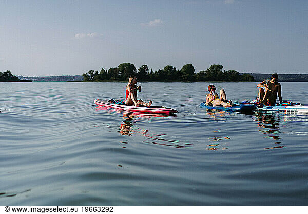 Friends drinking beer on a summer vacation on the lake  paddleboard.